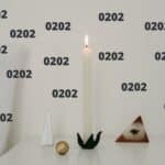 Image of candle burning on bedstand with a bunch of 0202 numbers floating around it